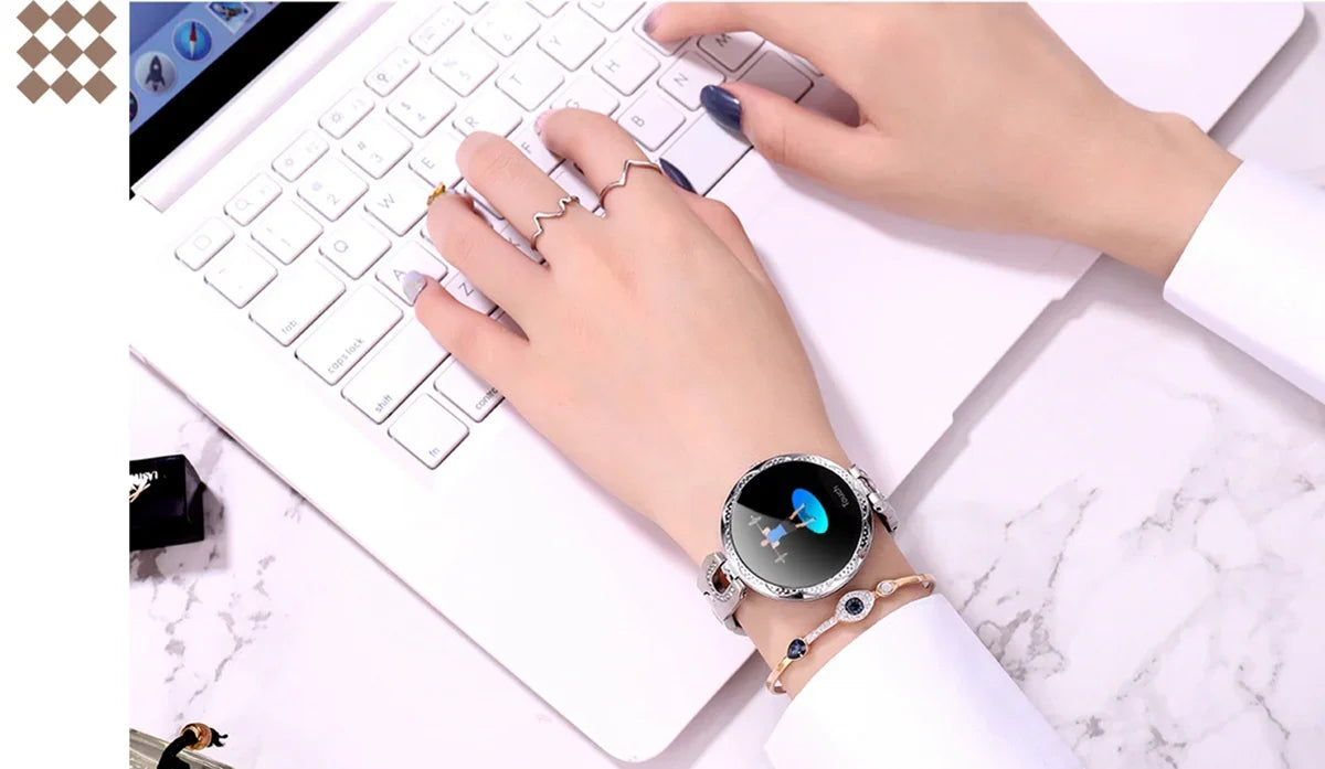 Woman wearing a stylish smart watch typing on a white laptop keyboard on marble desk