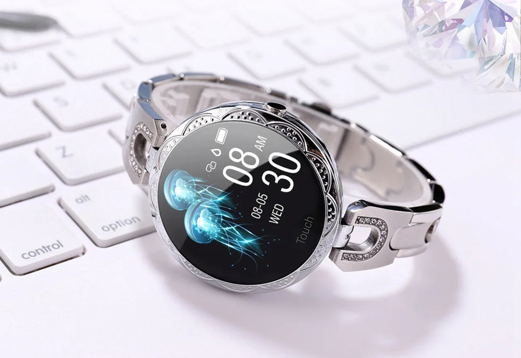 Elegant round silver smartwatch with jeweled band on white computer keyboard